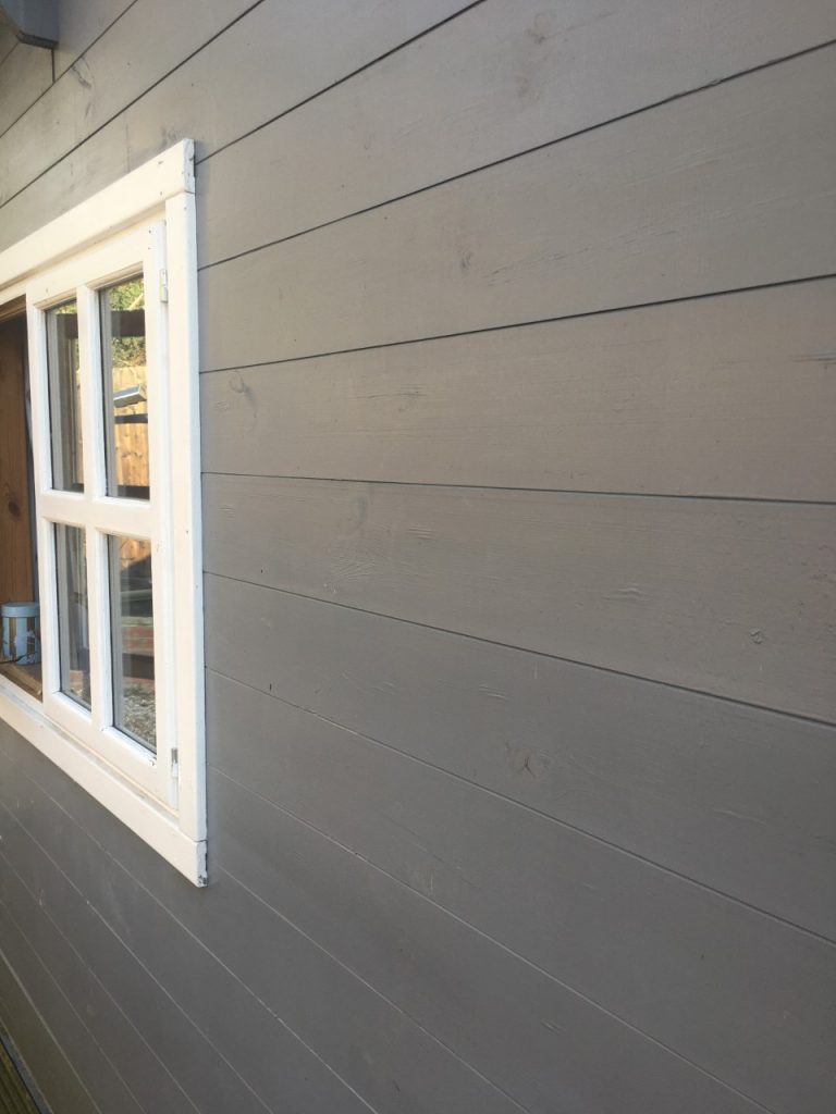 A wooden barn painted dark grey with a smooth finish