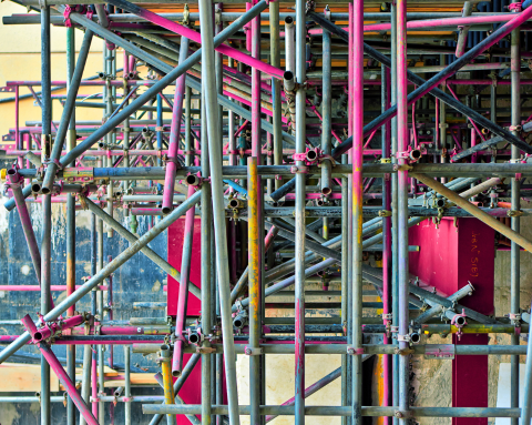 A complicated set of scaffolding, with different pieces painted pink, orange and blue